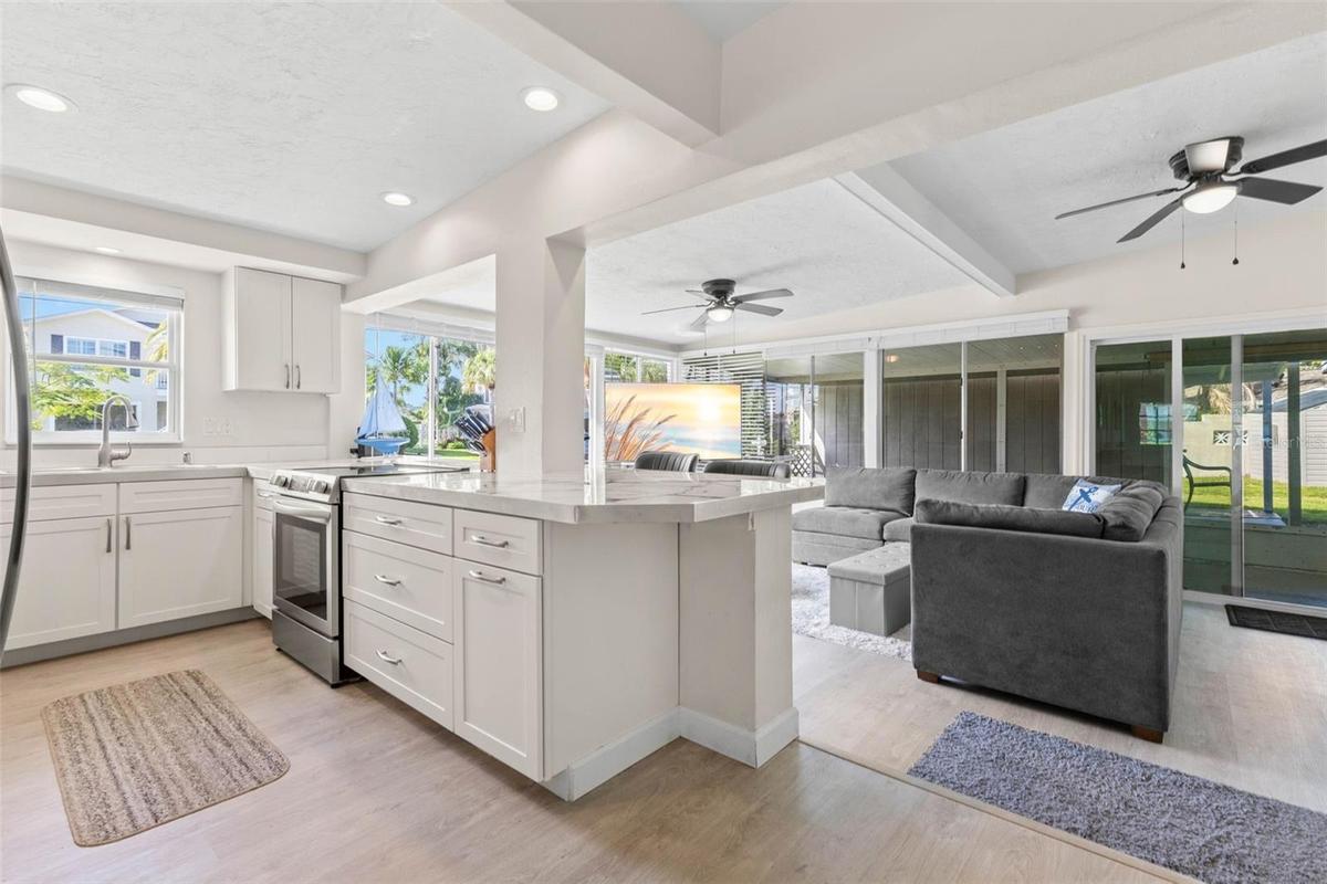 The updated kitchen (2025) opens directly to the living area and features crisp white cabinetry, stainless steel appliances, abundant counter space, r