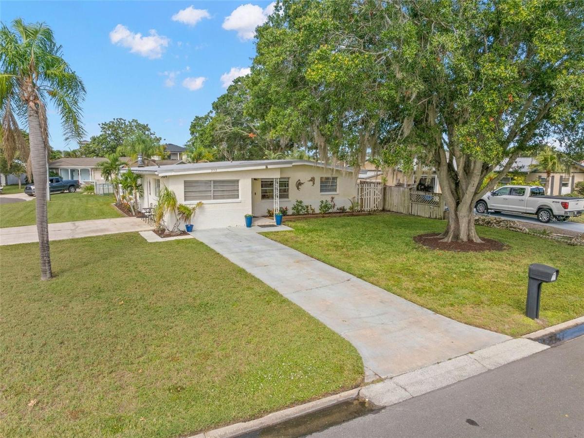 An elevated view highlights the home’s generous 11,800-square-foot corner setting, with a broad lawn, long driveway, mature shade trees, and the extra