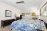The primary bedroom offers exceptional space for both sleeping and lounging, with multiple windows, a skylight, neutral tones, and luxury vinyl plank 