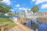 The waterfront setup is ready for serious boating, with a substantial wooden dock, 10,000-pound boat lift with davits, waterside storage, and a conven
