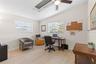 A bright secondary bedroom, currently used as a home office, offers two windows, a skylight, ceiling fan, neutral tones, and luxury vinyl plank floori