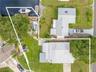 A straight-down aerial view highlights the property from street to canal, showing the generous yard, long driveway, screened lanai, RV parking area, a