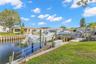The canal frontage is equipped for easy days on the water, with a 10,000-pound boat lift, wooden dock, railed access walkway, waterside storage, and a