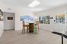 Step inside to a bright, open dining area with 2025 luxury vinyl plank flooring, a skylight overhead, and broad front windows that fill the space with
