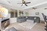 The spacious living room offers dual ceiling fans, luxury vinyl plank flooring, (2025) and a cozy fireplace, while a wall of windows and glass doors b