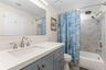 The remodeled primary bath (2025) pairs a wide gray vanity and sleek white countertop with a tiled tub/shower surround, rainfall showerhead, handheld 