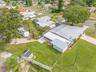 An aerial view shows just how much this property offers, with a broad backyard, RV parking area, screened lanai, workshop/storage space, and plenty of