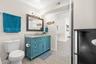 The updated second bath (2019) adds a splash of personality with a turquoise vanity, stone-look countertop, framed mirror, modern lighting, and plenty