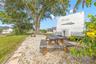 The oversized side yard offers dedicated space for RV, boat, or trailer parking, along with a gravel picnic area beneath a mature shade tree—another b