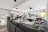 Expansive windows flood the living room with natural light, while the open connection to the updated kitchen, breakfast bar, ceiling fan, and fireplac