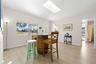 The bright dining area features 2025 luxury vinyl plank flooring, a skylight overhead, broad front windows, and plenty of room for everyday meals or e