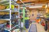 A dedicated workshop offers serious utility with abundant shelving, a long workbench, overhead storage, lighting, and plenty of room for tools, fishin