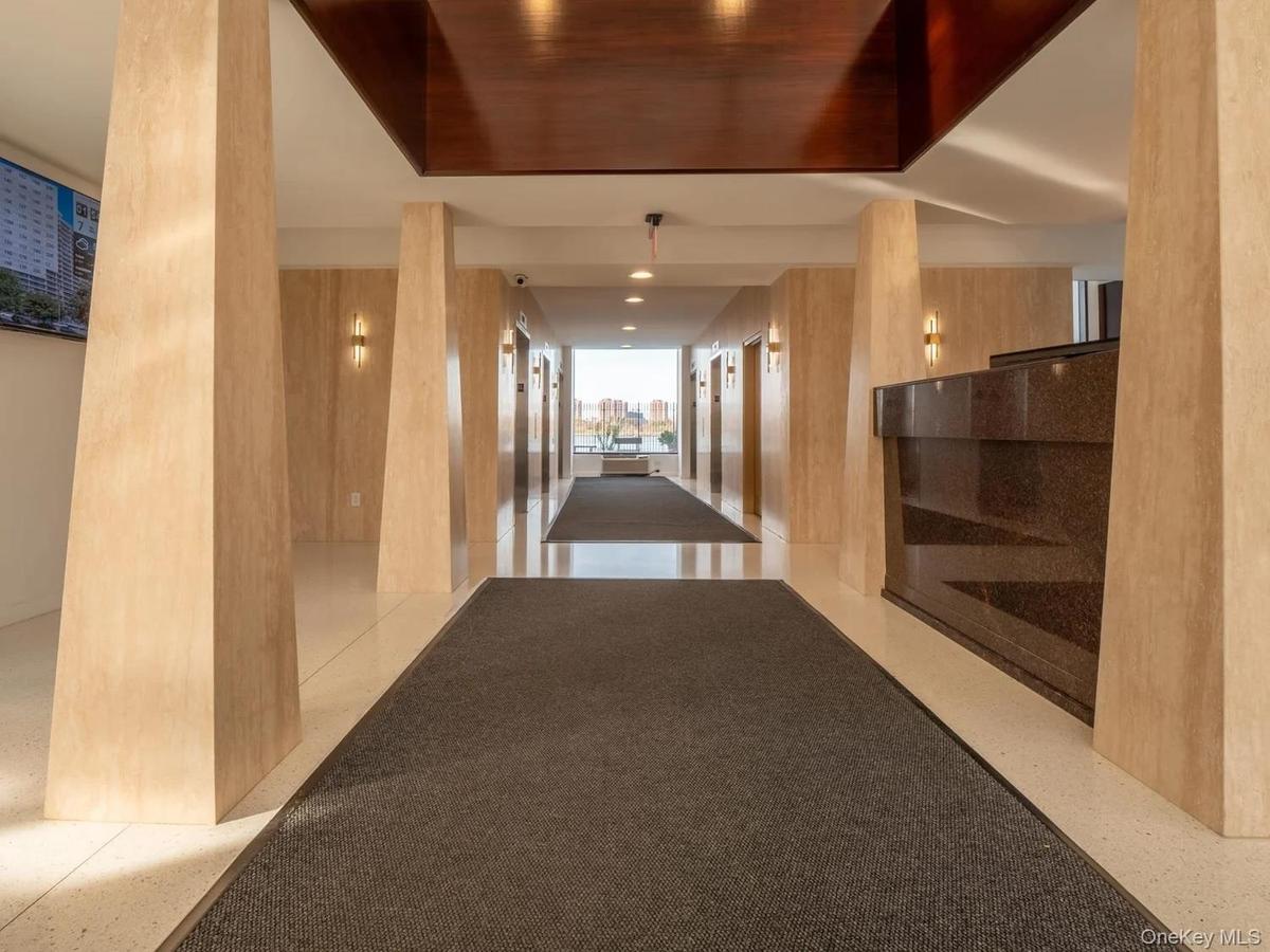Lobby with polished floor tile, integrated wall sconces, wood-finish ceiling accent, and a built-in reception desk