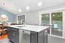 Kitchen island with white-veined countertop, integrated sink, and stainless steel dishwasher