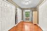 Hardwood-flooring, multiple paneled doors, single window, and a ceiling-mounted light fixture-Primary Closet