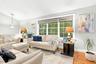 Spacious living area featuring large windows, wood flooring, and a decorative pendant light fixture in foyer area.