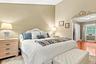 Vaulted ceiling with light-toned walls, rich wood-finish flooring, and a decorative archway