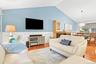 Vaulted ceiling, wood-flooring, wainscoting, fireplace with built-in cabinetry, and a modern dining pendant light
