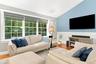 Vaulted ceiling, hardwood flooring, large multi-pane windows, decorative wainscoting, and a wall-mounted display space