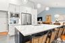 Kitchen featuring white cabinetry, stainless steel appliances, a large island with a countertop, and pendant lighting