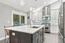Gourmet kitchen featuring a center island with sink, white countertops, built-in stainless steel appliances, and light wood-finish flooring