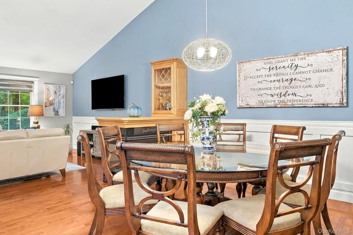 Vaulted ceiling, chair rail molding, wood-flooring, built-in cabinetry, and a decorative pendant light fixture