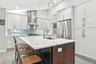 Kitchen featuring a central island with a Quartz countertop, white shaker cabinetry, stainless steel appliances, and a tile backsplash