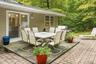 Patio area featuring a sliding glass door, a brick paver section, and mature trees in the background