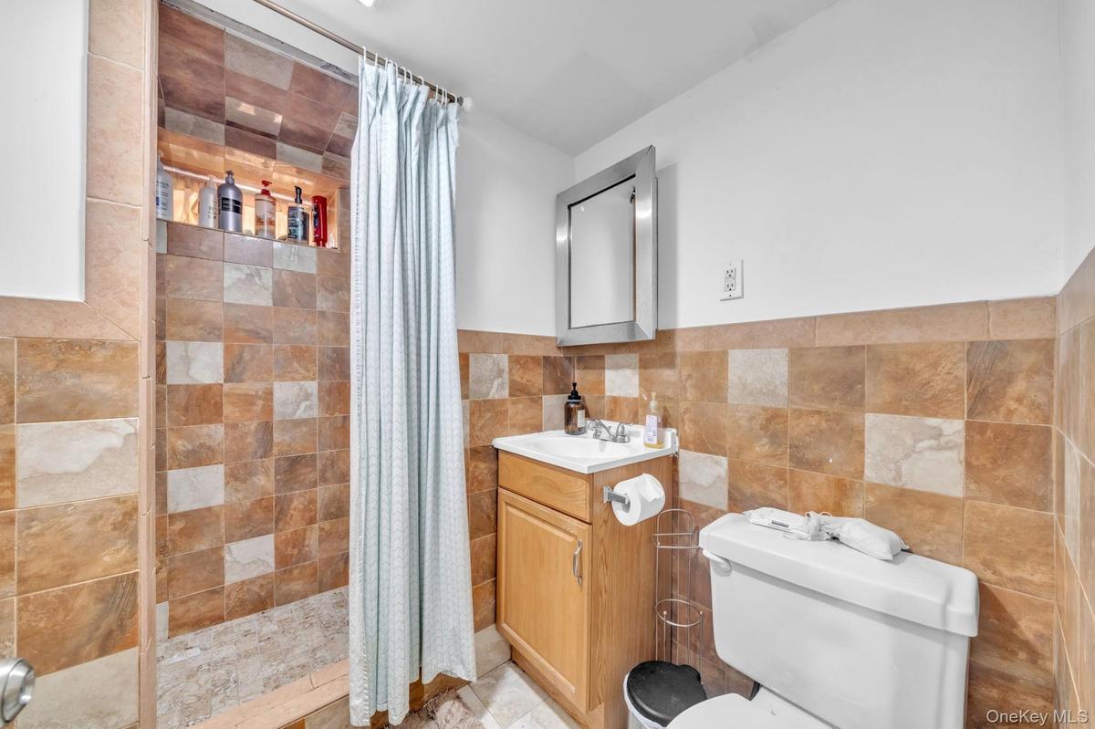 Tiled shower with an integrated niche, wood-finish vanity, and a framed mirror
