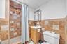 Tiled shower with an integrated niche, wood-finish vanity, and a framed mirror