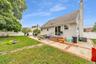 Expansive backyard featuring a manicured lawn, white privacy fencing, a brick and concrete patio.