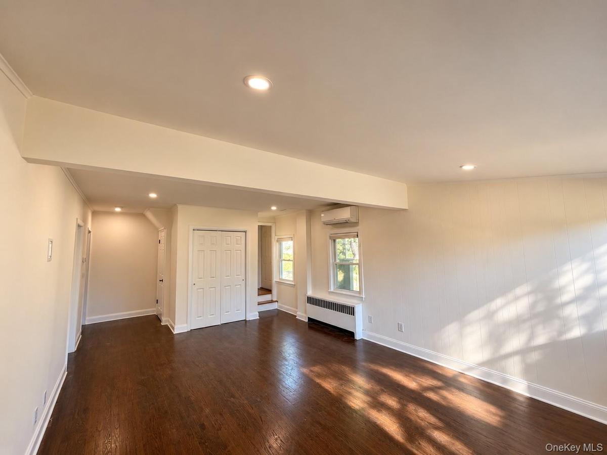 Hardwood flooring, recessed lighting, air conditioning unit, and white bi-fold closet doors