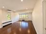 Wood-finish flooring throughout, recessed lighting, white paneled walls, multiple windows, and a split-system air conditioning unit