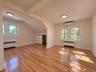 Hardwood flooring, multiple windows, built-in air conditioning unit, ceiling-mounted lighting, and a closet with bifold doors