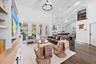 Vaulted white ceilings with exposed beams, wood-look tile flooring, built-in media console with shelving, white French doors, and an upper-level inter