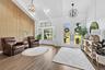 Vaulted ceiling with exposed beams, wood-look tile flooring, accent wall with vertical wood paneling, dual glass-paneled entry doors, and built-in win