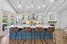 Kitchen featuring a large island with white countertop, stainless steel appliances, exposed ceiling beams, and a fireplace with a brick surround