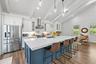 Vaulted ceiling with exposed beams, stainless steel appliances, central island with seating, pendant lighting, and wood-finish flooring