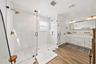 Glass-enclosed shower with gold-toned fixtures and hexagonal tile flooring