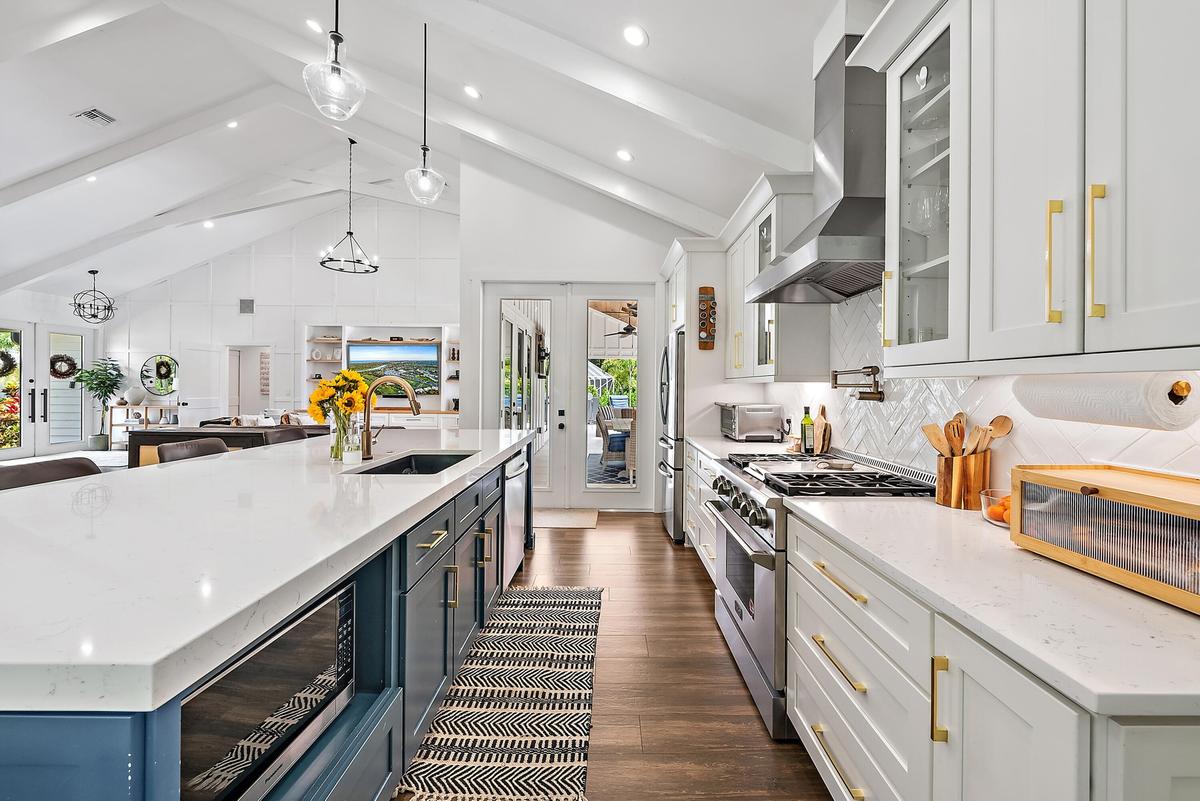 Open-concept kitchen with vaulted ceilings, recessed lighting, wood-finish flooring, a kitchen island with built-in microwave, and stainless steel app