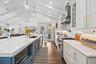 Open-concept kitchen with vaulted ceilings, recessed lighting, wood-finish flooring, a kitchen island with built-in microwave, and stainless steel app
