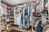 Custom-built closet system featuring wood-finish flooring, white cabinetry, extensive shelving, integrated drawers, and ample hanging rods
