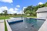 Pool area featuring a tiled water feature, light-toned paver decking, and an adjacent structure with a metal roof