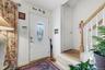 Entryway featuring a white door with an oval decorative glass insert, wood-finish flooring, a wood banister, and white balusters