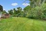 Expansive green lawn with mature perimeter trees and a l wooden deck