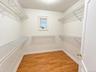Walk-in closet with wire shelving, wood-finish flooring, and a window for natural light