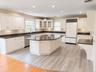 Expansive kitchen featuring white cabinetry, dark stone countertops, a large center island, and integrated stainless steel appliances