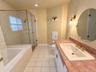 Spacious bathroom featuring a glass-enclosed shower, built-in bathtub, vanity with a rectangular sink, and tile flooring