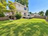 Expansive lawn area with a wood deck, wood privacy fencing, and mature landscaping