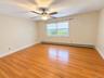 Hardwood flooring, white window trim, ceiling fan with integrated lighting, baseboard heating unit